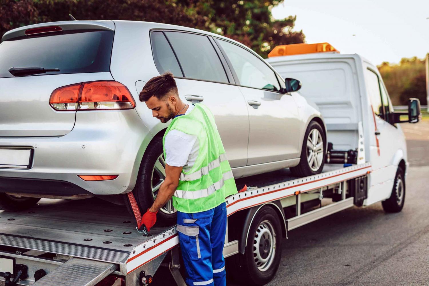 Man loading a car onto a tow truck